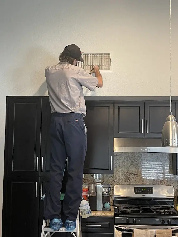 Technician inspecting an air vent during HVAC service in World Golf Village